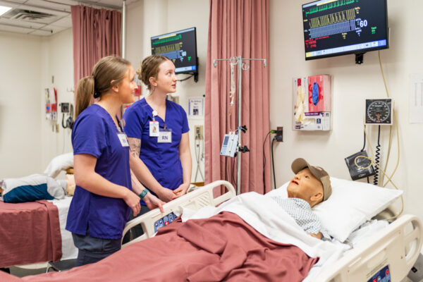 Two nursing students interact with a mannikin in the WSU Simulation Lab.