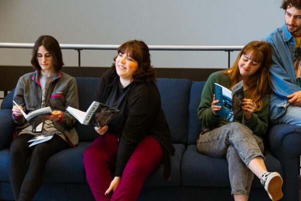 Students sit together with books during an author event on campus.