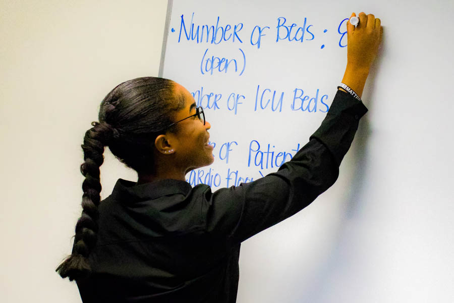 WSU female student smiling and writing on a whiteboard.