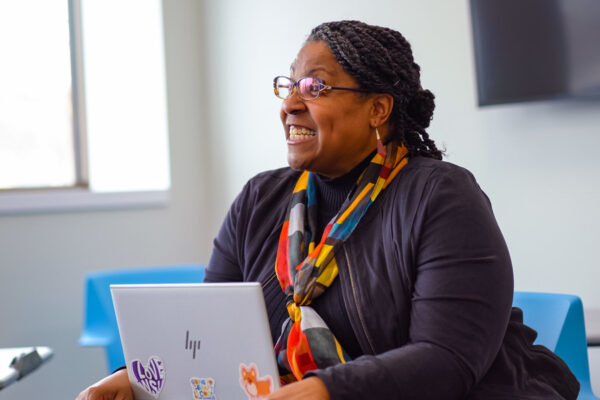 An adult student looks up from her laptop to have a conversation with another person in class on the Winona State campus.