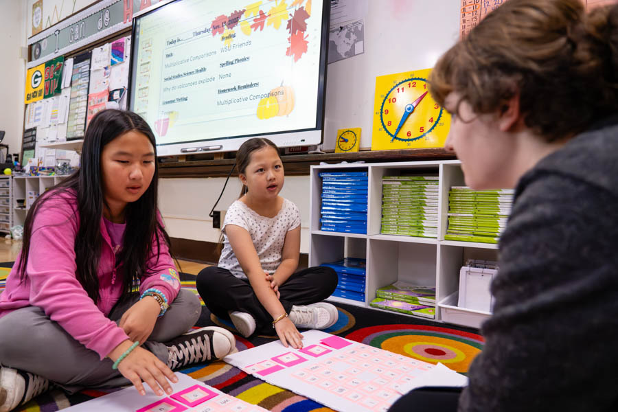 WSU student teacher sitting with young children.