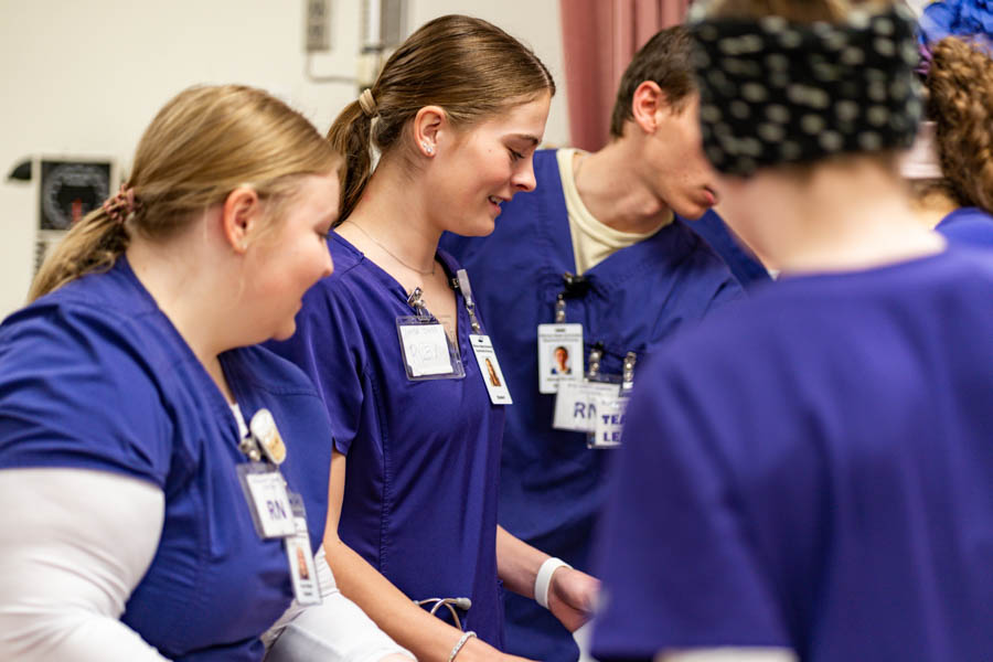 Group of co-ed Nursing students wearing scrubs during a simulation lab at Winona State.