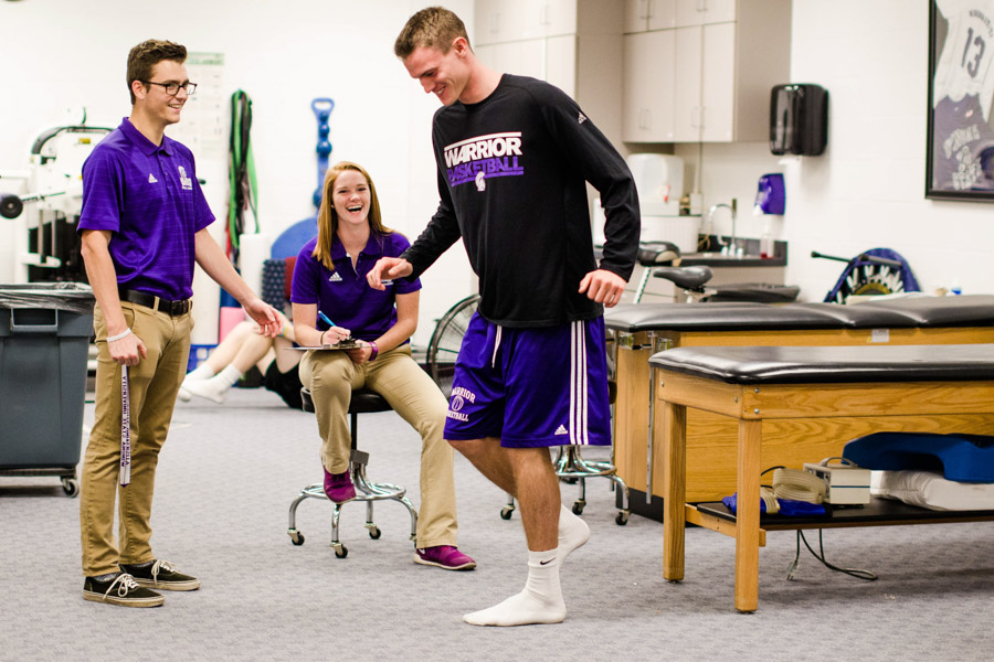 Two WSU students work with a young man in the WSU Athletic Training facility.