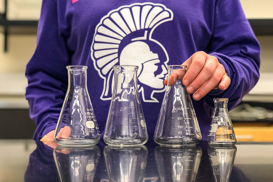 A WSU student arranges beakers on a table.