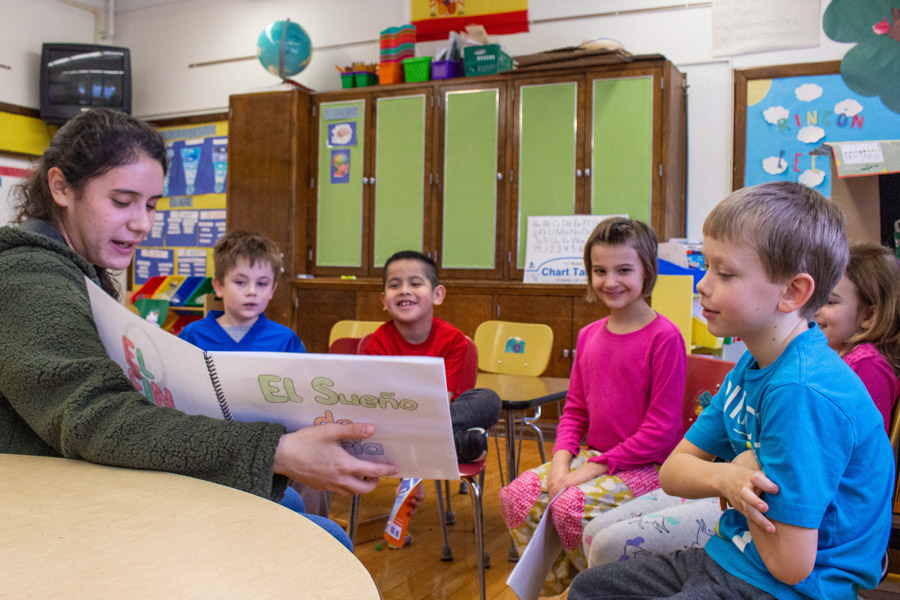A WSU student teacher reads a book in Spanish to a group of kids.