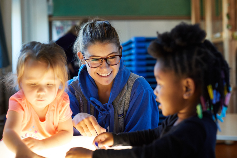A female student teacher works with two young kids in the WSU Children's Center.