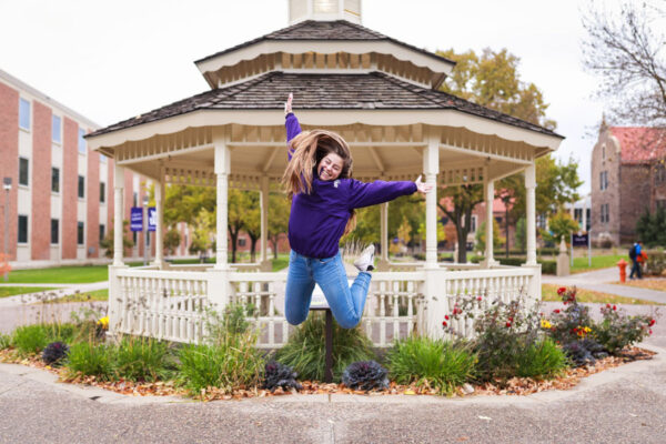 A female students jumps excitedly in front of the WSU Gazebo.