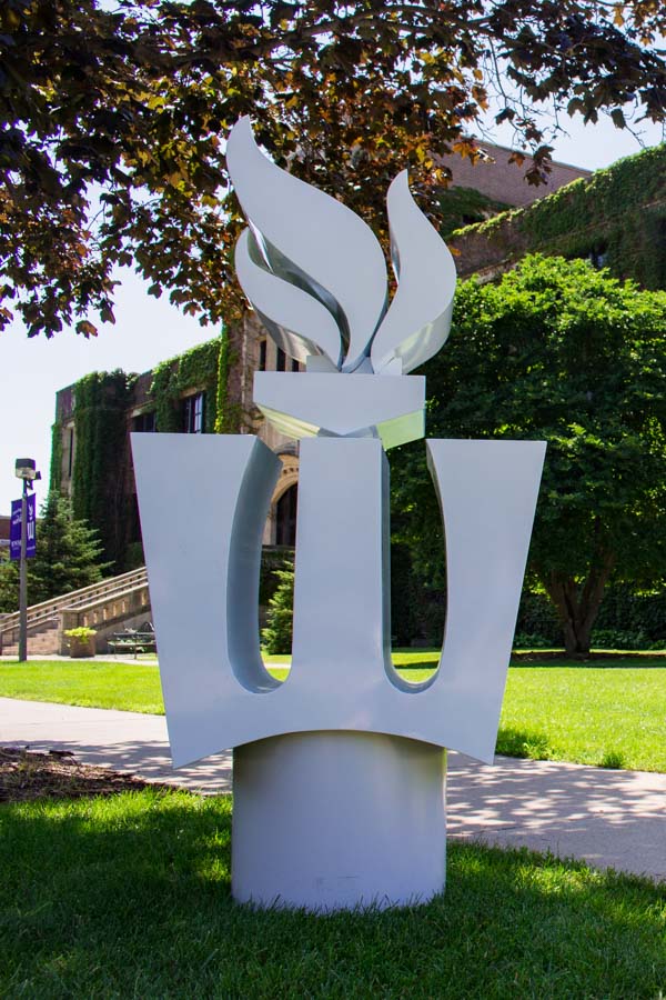 A white metal sculpture of the WSU Flaming W stands outside Somesen Hall.