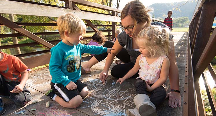 Children and woman coloring with chalk 
