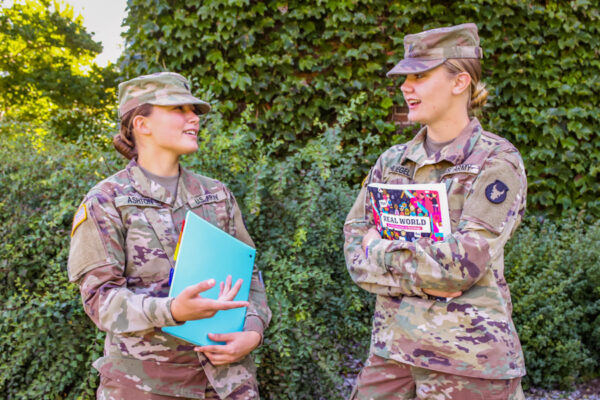 Female students wearing military uniforms chat on campus.