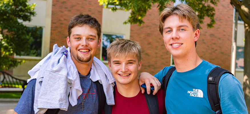 Three male students on campus pose together on the WSU Winona campus.