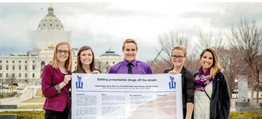 WSU Public Health students pose with their research poster at the Minneosta State Capitol.