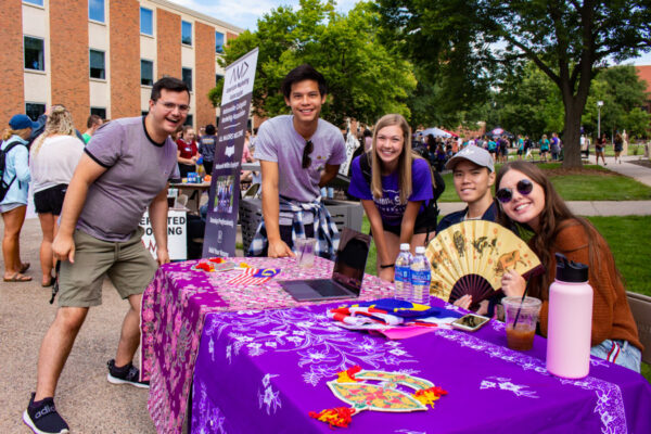 Students pose together at their club table during the club fair.