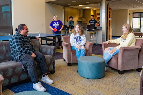 A group of students hang out and play games in their residence hall lounge.