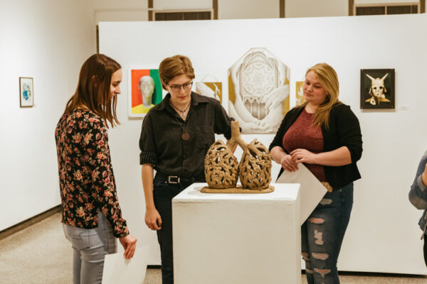 Thee female students look at a sculpture in an art gallery at WSU.