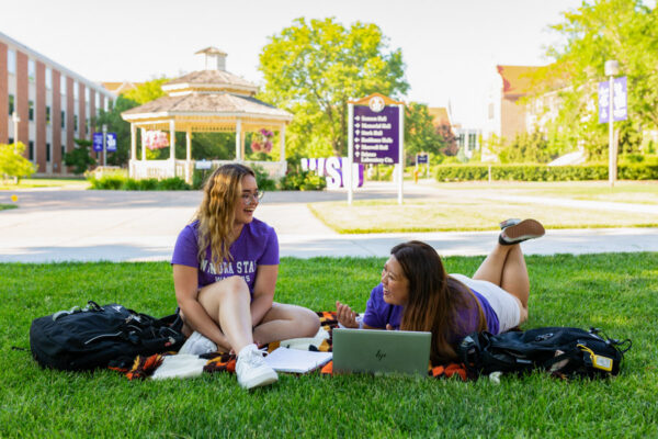 Two female students study outside on Winona campus by the gazebo.
