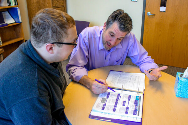 A male student works with a WSU advisor to plan a course schedule.