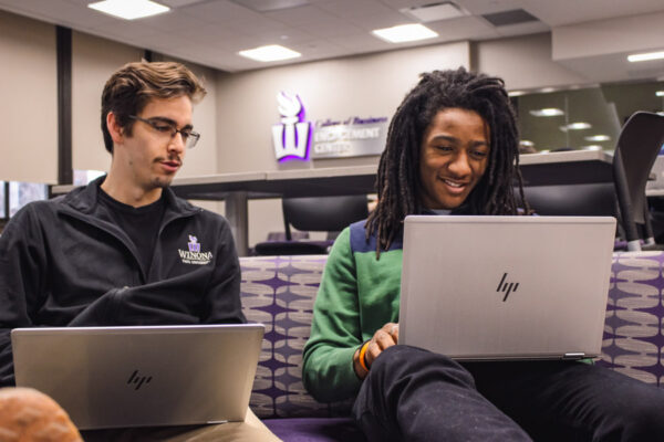 Two male students work on laptops in the Business Engagement Center.
