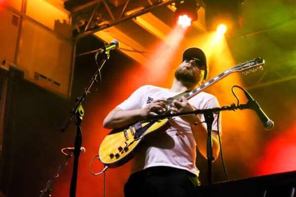 A male guitarist performs on stage during a concert.