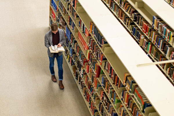 A WSU student reads a book while walking through the Krueger Library.