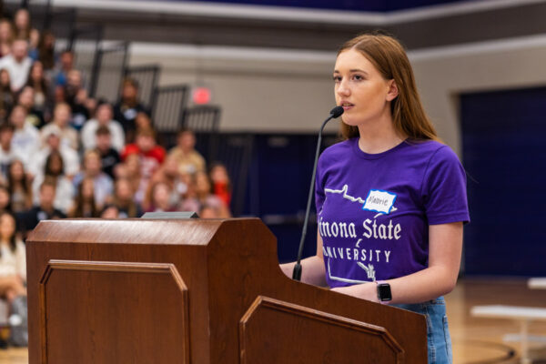 A female student gives a presentation to an audience in the McCown Gym.