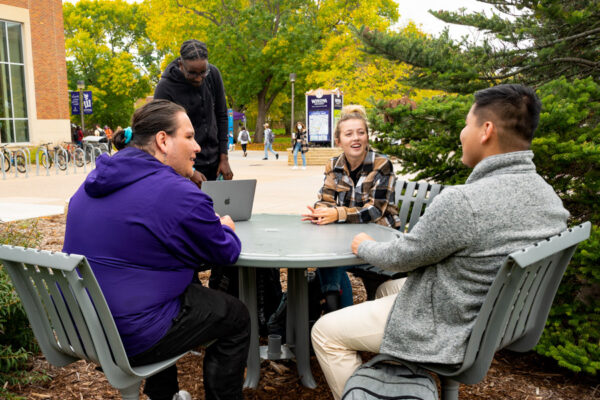 A group of students hang out around a picnic table on the WSU Winona campus.