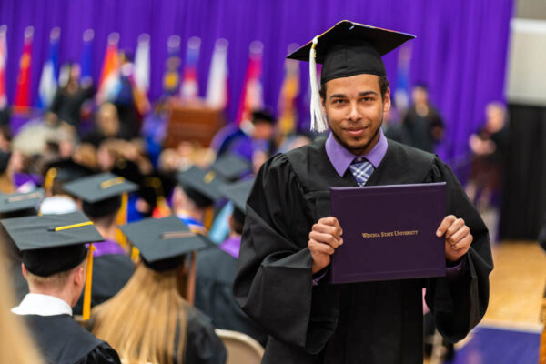 A male graduate proudly holds a diploma during the WSU Commencement Ceremony.