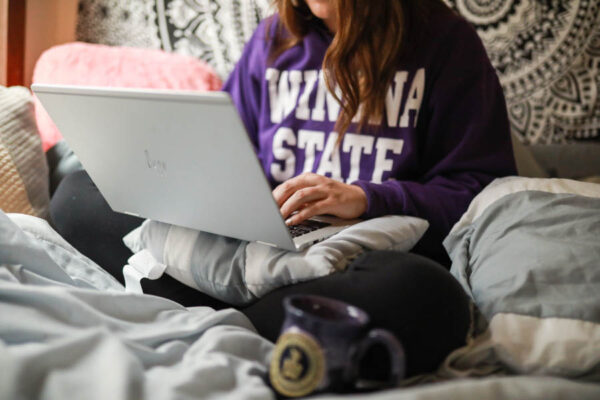 A WSU student uses a laptop while in bed.