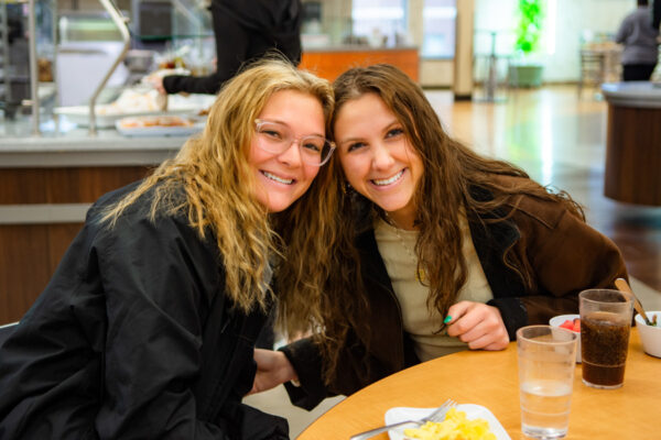 Two female students pose together and smile during an event on WSU campus.