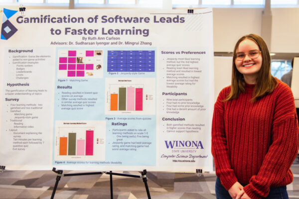 A female student poses next to a research poster.
