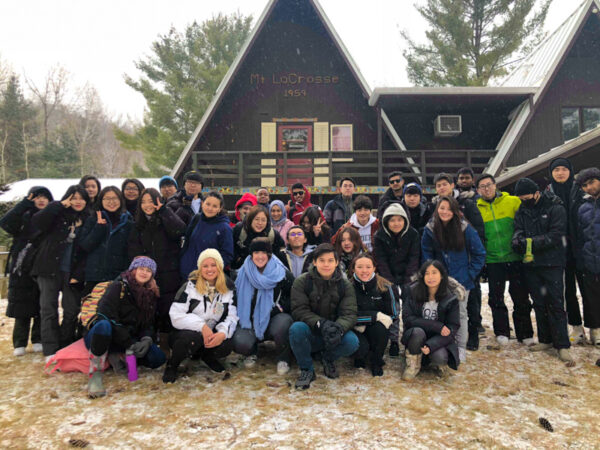A large group of international students pose together while on a trip to a ski lodge.