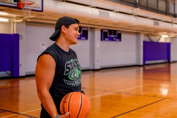 A male student holds a basketball in the WSU Fitness Center gym.