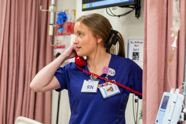 A nurse answers a phone call in a clinic setting.