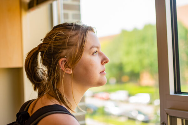 A female student looks out a window in a residence hall on WSU campus.