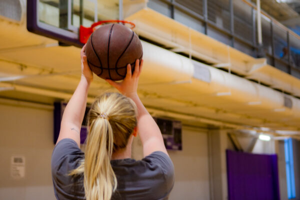 A female student prepares to shoot a basketball into the net in the gym on WSU campus.