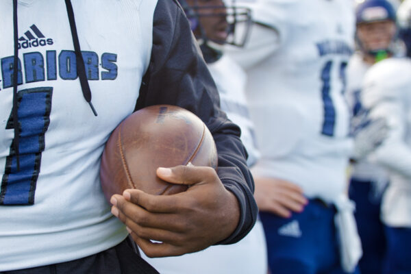 A WSU football player holds a football.