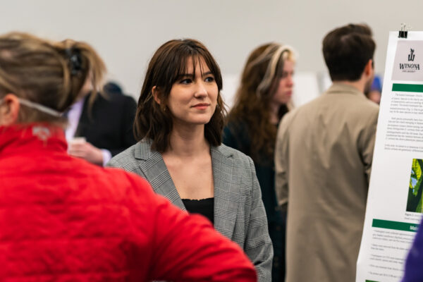 A student presents their research to a group at a campus event.