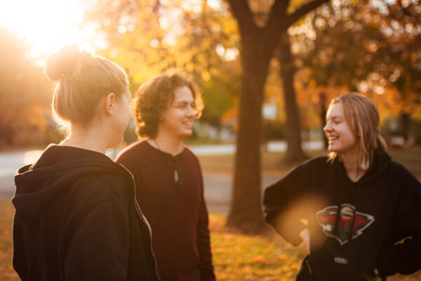 Three students chat on a sunny fall afternoon on the WSU campus.
