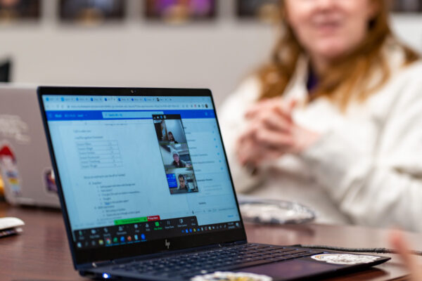 Two students work on laptops with each other.