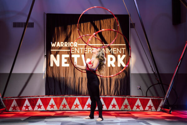 A female performer juggles hula-hoops on stage during an event on campus.