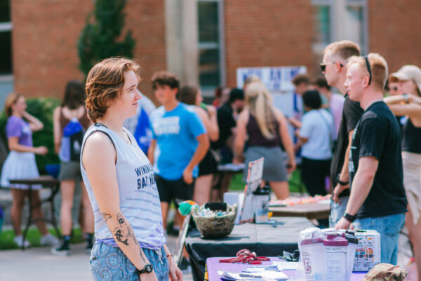 A student talks to club members behind a table display during the WSU Club Fair on Winona campus.