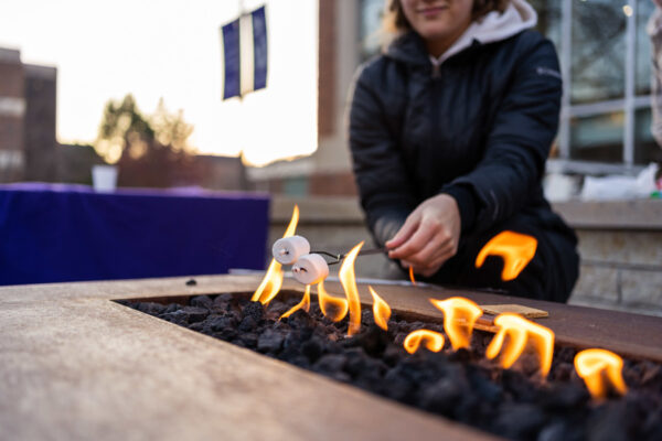 A student roasts marshmallows on the Fire Feature Patio.