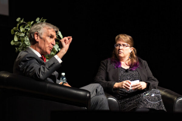 A moderater asks Bill Nye questions on stage during a campus event.