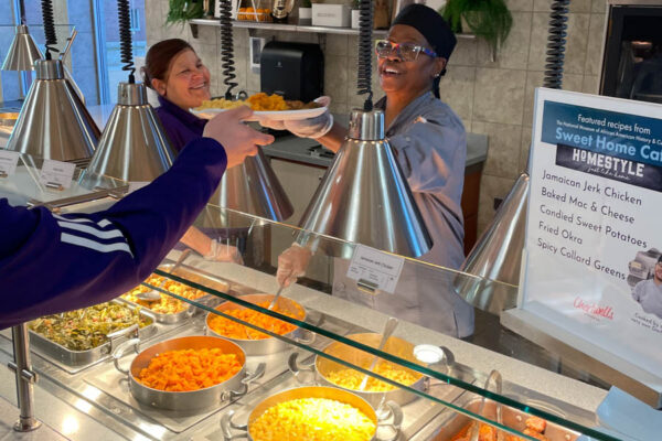 A dining staff member hands a student a plate of food in the Jack Kane Dining Center on the WSU campus in Winona.