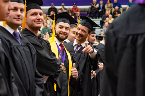 A happy graduate in a cap and gown points out from the crowd during the WSU Commencement ceremony.