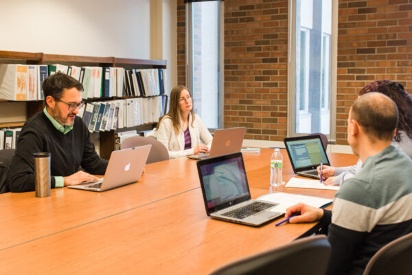 A group of faculty and staff have a meeting in a conference room at WSU.