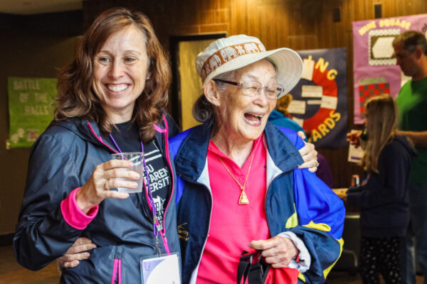 A retiree laughs with a friend at a campus event.