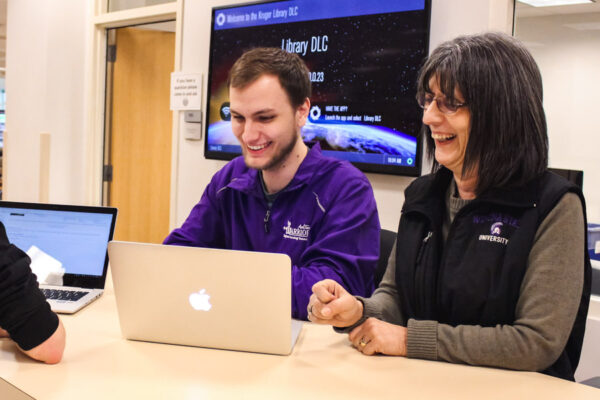 A supervisor guides a student employee in the WSU library.