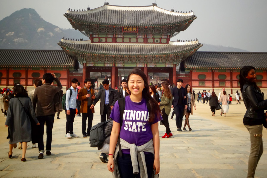 While studying abroad in China, a female student poses in front of a historical building.