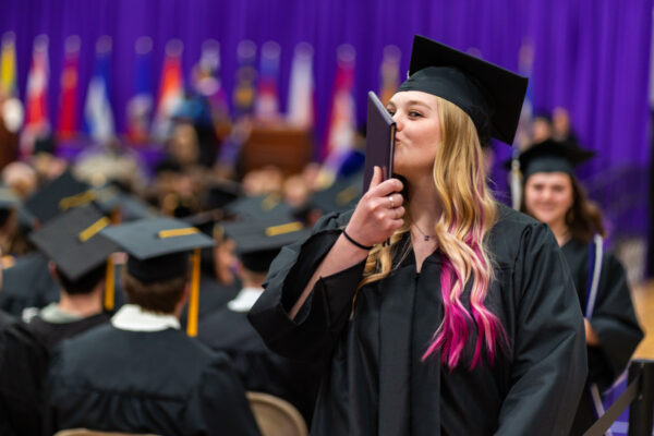 A graduate kisses her diploma as she leaves the stage during the WSU Commencement Ceremony.
